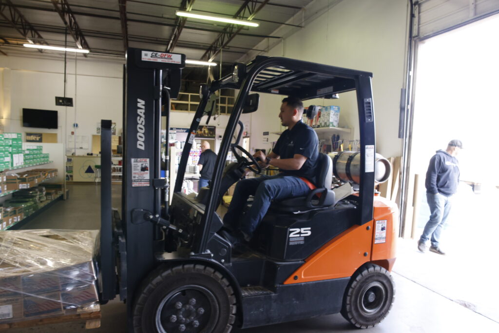 Amen operating a forklift inside of a warehouse